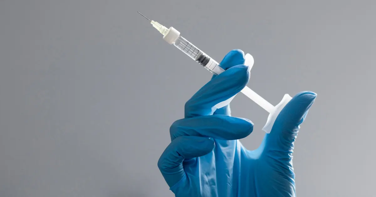 A gloved hand holding a syringe